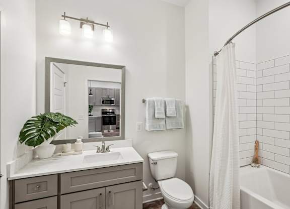 A bathroom with a white sink, toilet, and bathtub with subway tiled surround at Tapestry University Park apartments in Sarasota, FL.