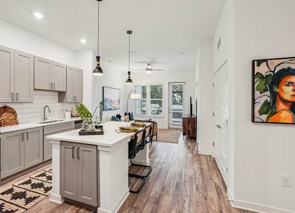 A kitchen with a white island and wooden floors at Tapestry University Park apartments in Sarasota, FL