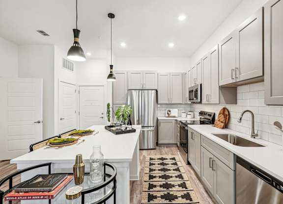 A modern kitchen with a white island and stainless steel appliances at Tapestry University Park apartments in Sarasota, FL