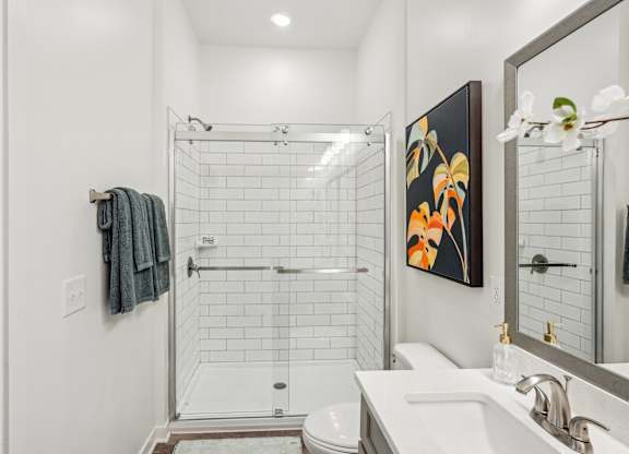 A bathroom with a white sink, toilet, and a shower with a glass door at Tapestry University Park apartments in Sarasota, FL