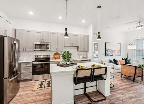 A modern kitchen with a white island and stainless steel appliances at Tapestry University Park Apartments in Sarasota, FL