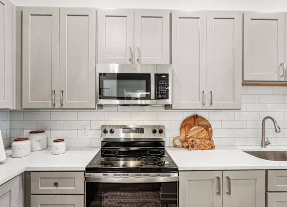 A kitchen with a stove, microwave, and custom cabinetry at Tapestry University Park apartments in Sarasota, FL