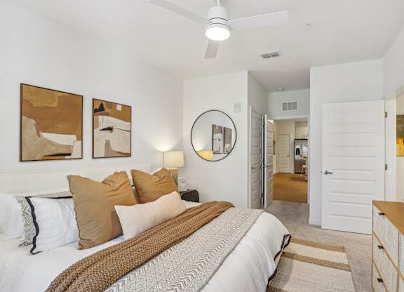 A bedroom with a bed, a ceiling fan, and a mirror.