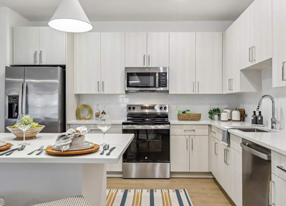 A modern kitchen with white cabinets and stainless steel appliances.
