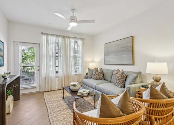A living room with a grey couch, a wooden table, and a painting on the wall.
