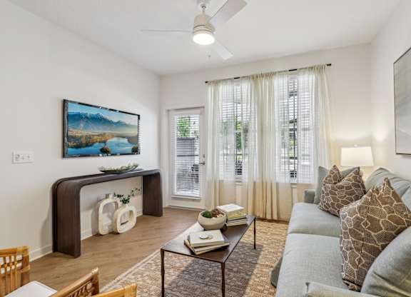 A living room with a grey couch and a painting on the wall.