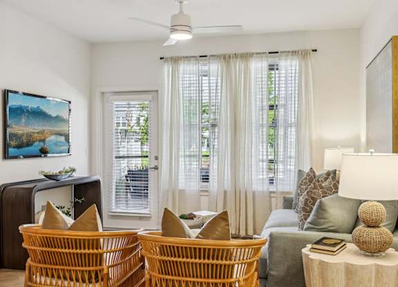 A living room with a sofa, two chairs, and a table with a lamp on it.