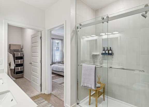 A white bathroom with a walk-in shower and a towel rack.