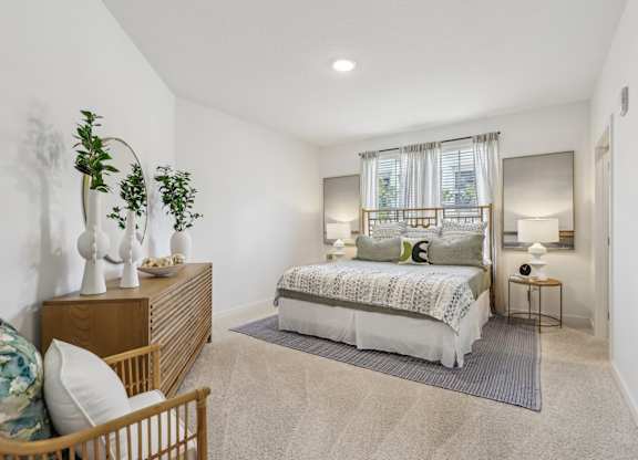 A bedroom with a bed, nightstand, and a plant.