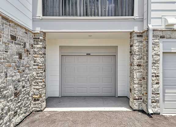 A white garage door is flanked by two stone pillars.