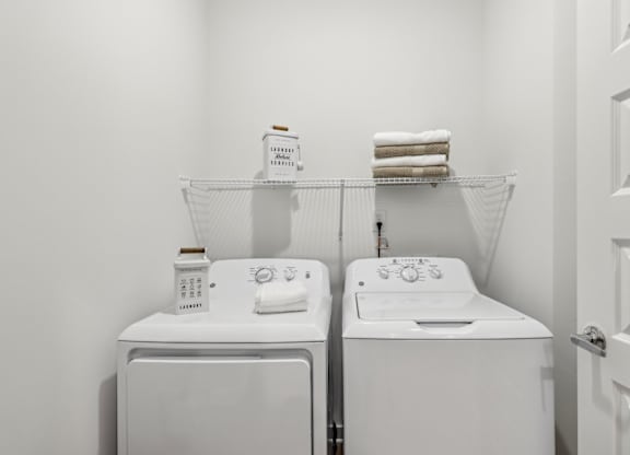 A white laundry room with two washing machines and a towel rack.