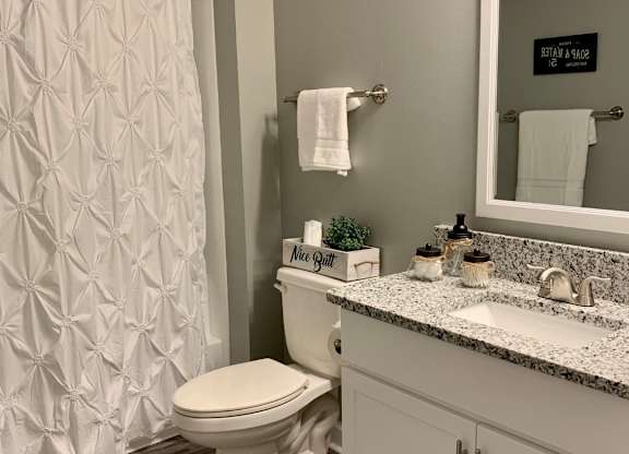 bathroom with wood flooring and granite countertops at The Avery at Auburn Apartments in Auburn, AL