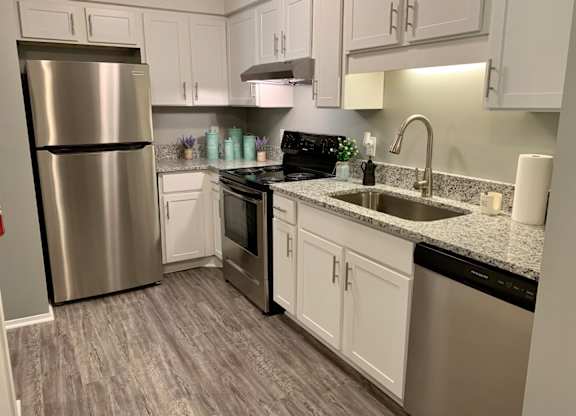 Kitchen with stainless steel appliances, wood style flooring, and gooseneck faucet at The Avery at Auburn Apartments in Auburn, AL
