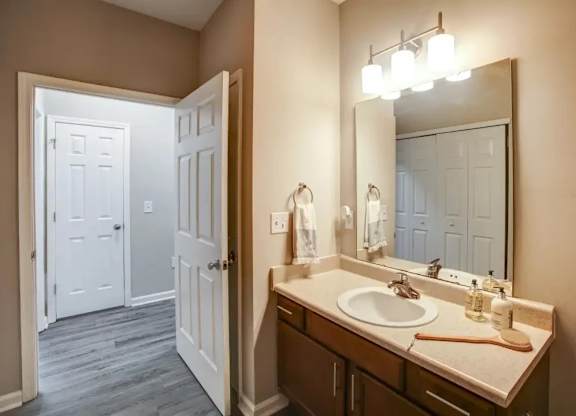 A bathroom with a white door and a brown vanity.