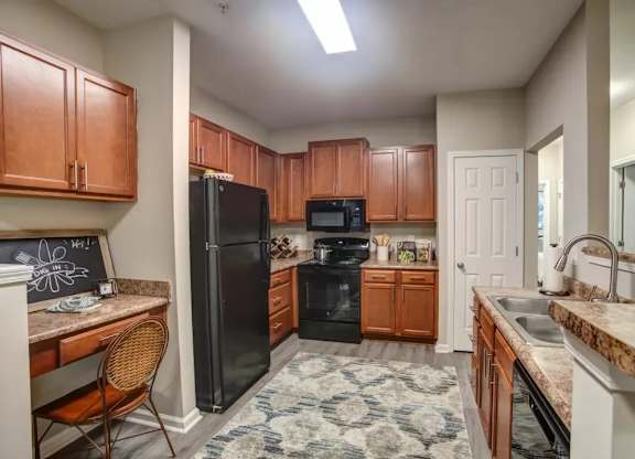 A kitchen with brown cabinets and a black refrigerator.