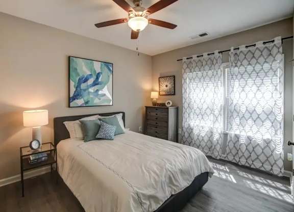 A bedroom with a bed, nightstand, and a painting on the wall.