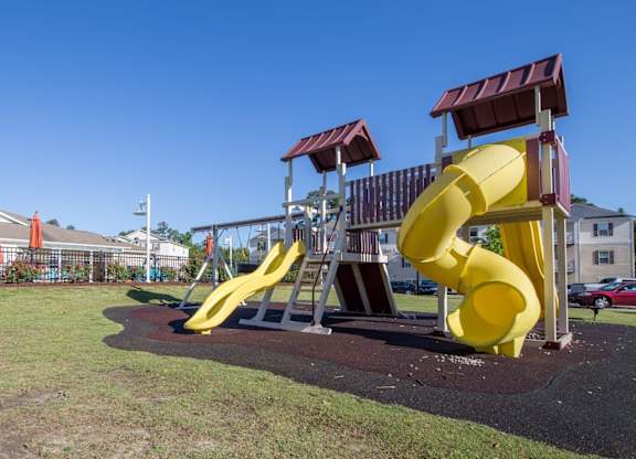 A playground with a yellow slide and a red roofed structure.