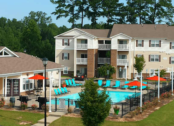 A large apartment complex with a pool and a fence.