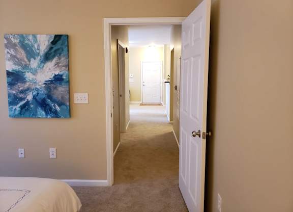 A hallway with a white door and a painting on the wall.
