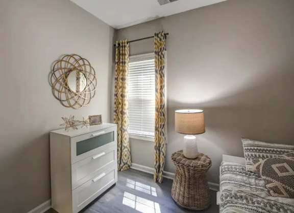 A bedroom with a bed, nightstand, and window with curtains.