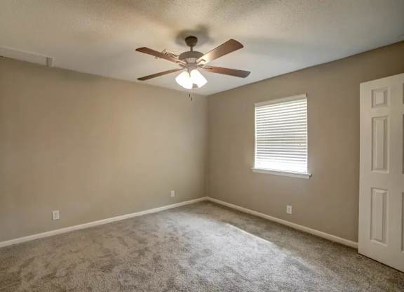 A room with a ceiling fan and a window with blinds.