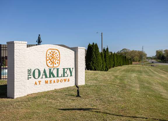 A sign that says "The Oakley at Meadows" stands in a grassy field.