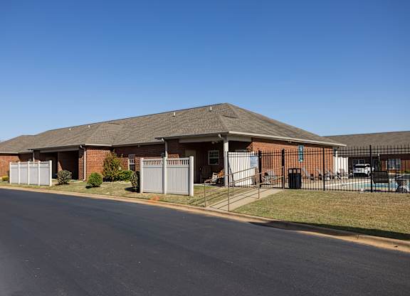A long building with a grey roof and a fence in front of it.
