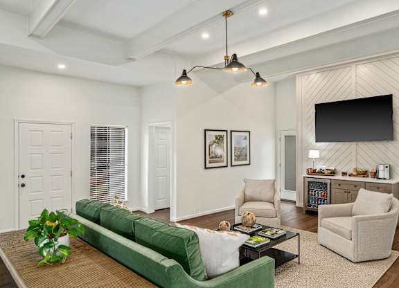 A living room with a green couch and a television on the wall.