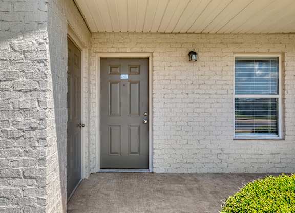 A grey door is on the front of a white brick house.