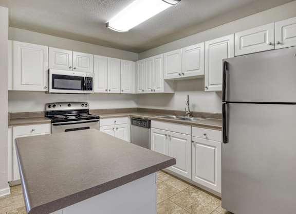 A kitchen with white cabinets and a stainless steel refrigerator.