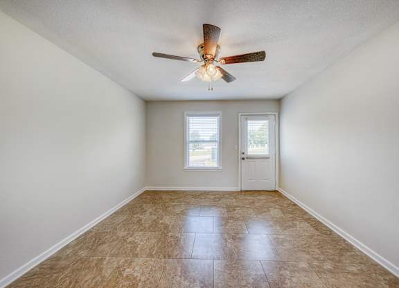 A room with a ceiling fan and two windows.