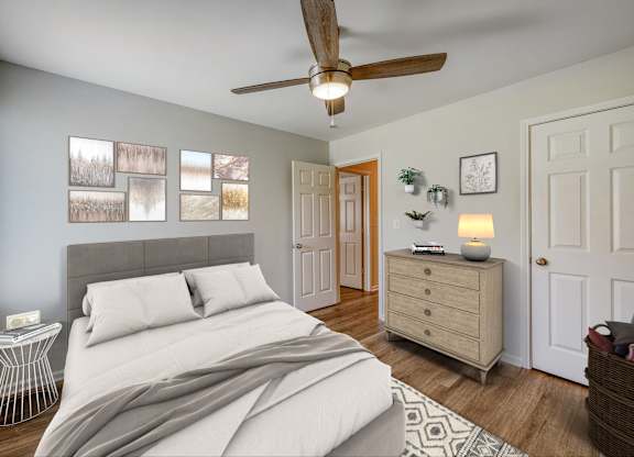 A bedroom with a bed, a ceiling fan, and a nightstand with a lamp.
