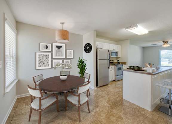 A kitchen with a table and chairs in the foreground and a refrigerator and microwave in the background.