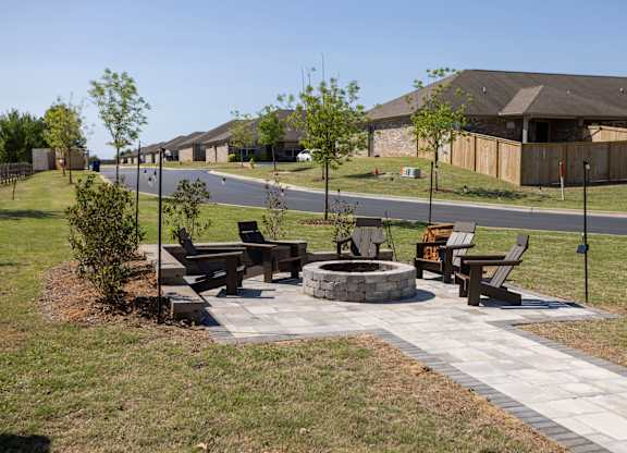 A park with a fire pit and benches.