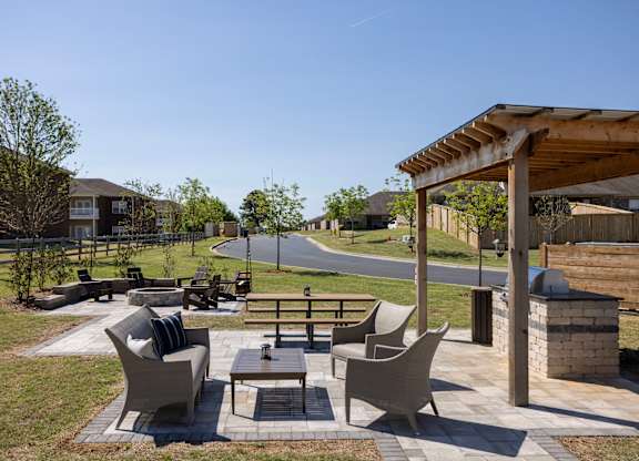 A patio with a table and chairs is surrounded by a grassy area.
