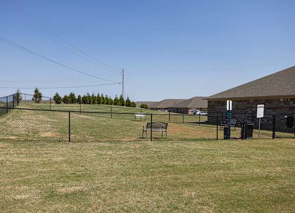 A grassy field with a fence and a bench.