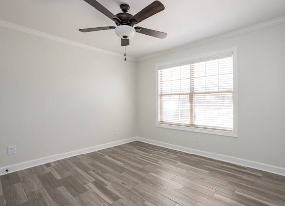 A room with a ceiling fan and a window with blinds.