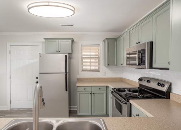 A kitchen with a stainless steel refrigerator and a stove top oven.