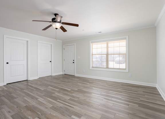 A room with a ceiling fan and wooden flooring.