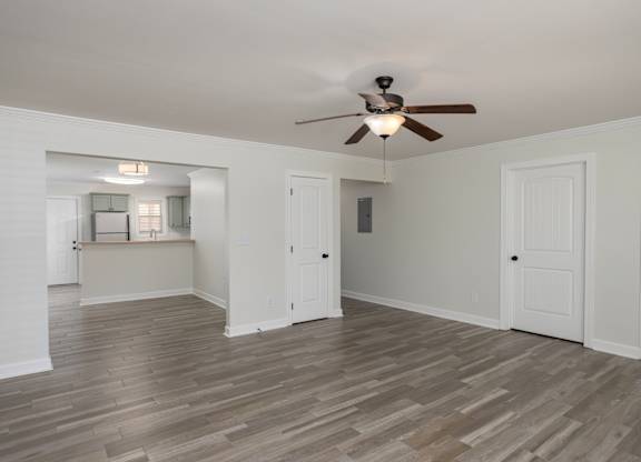 A room with a ceiling fan and wooden flooring.