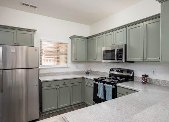 A kitchen with a refrigerator, microwave, oven, and cabinets.