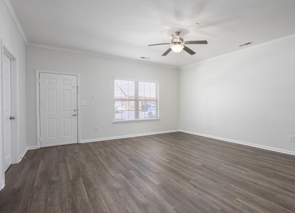 A room with a ceiling fan and wooden flooring.
