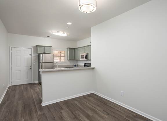 A kitchen area with a refrigerator, cabinets, and a countertop.