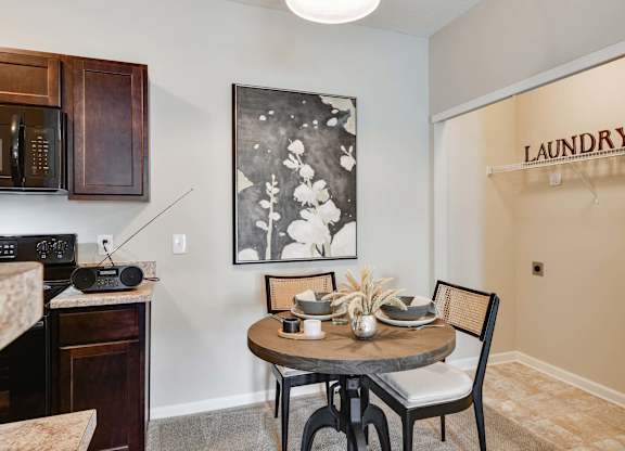 A dining room with a table set for two and a laundry sign on the wall.