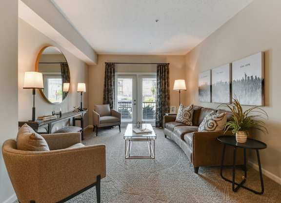 A well-lit living room with a sofa, armchair, and coffee table.