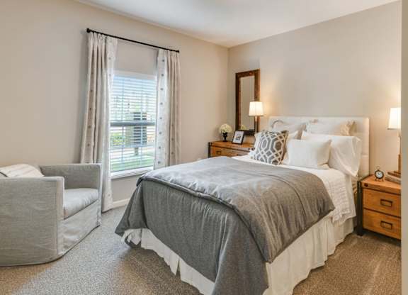 A bedroom with a large bed and a chair.