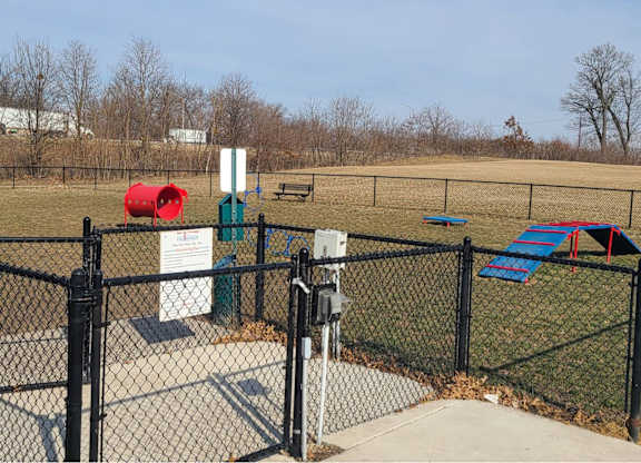 a dog park with a chain link fence and playground equipment t The Pomenade at Founders Square Apartments in Portage, IN