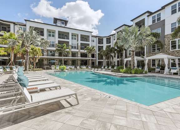 a swimming pool with lounge chairs and a building in the background