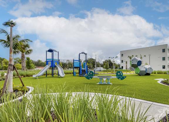 A playground with a blue slide and a white building in the background.