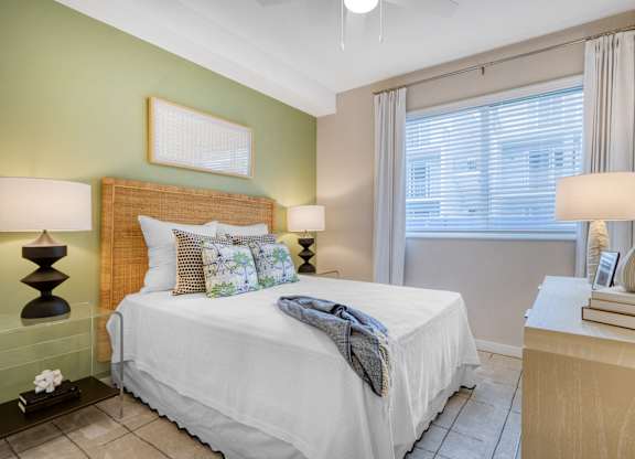 A bedroom with a white bed and a green wall.